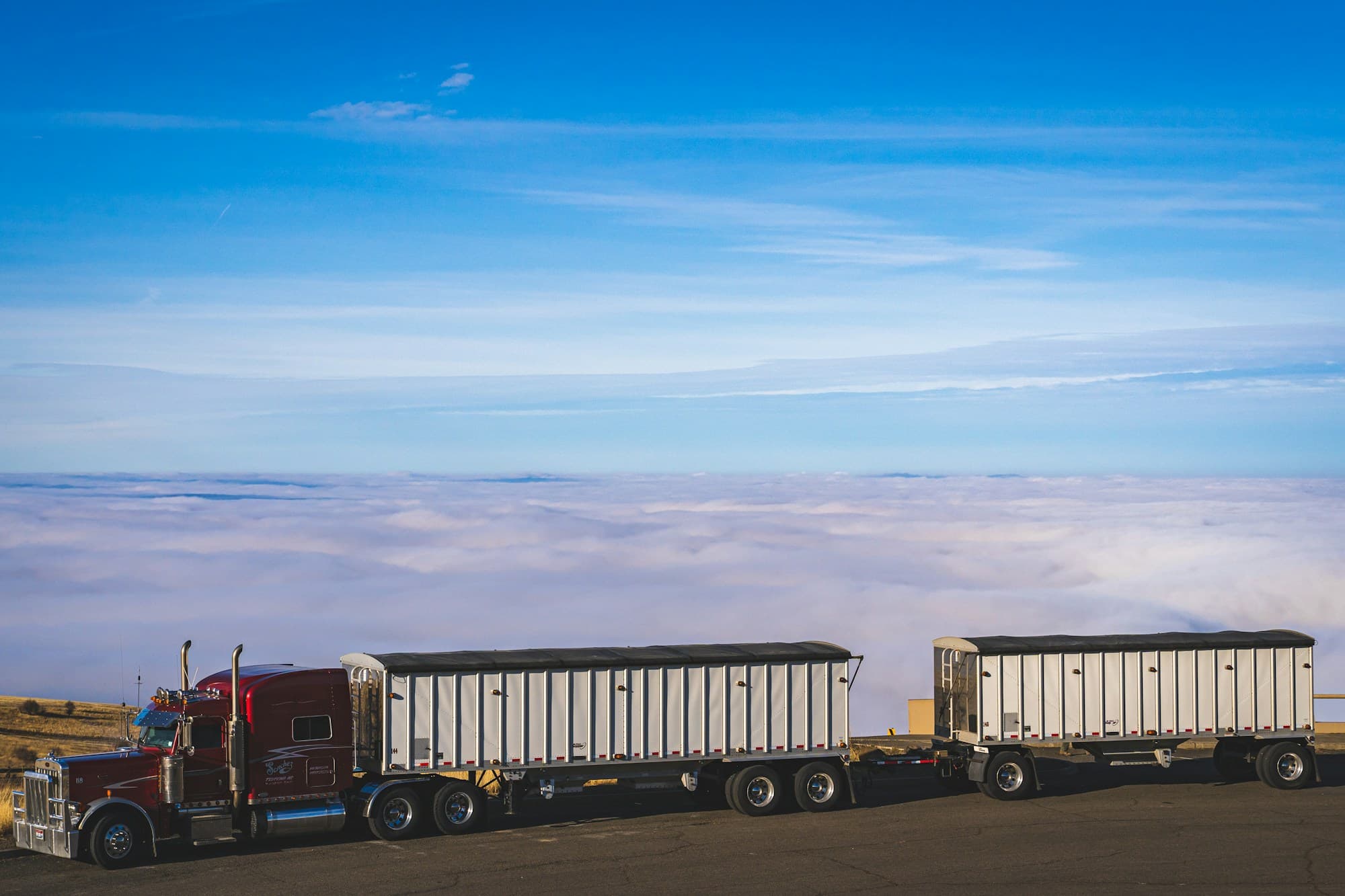 A heavy-duty tractor with freight trailers parked by a mountain highway